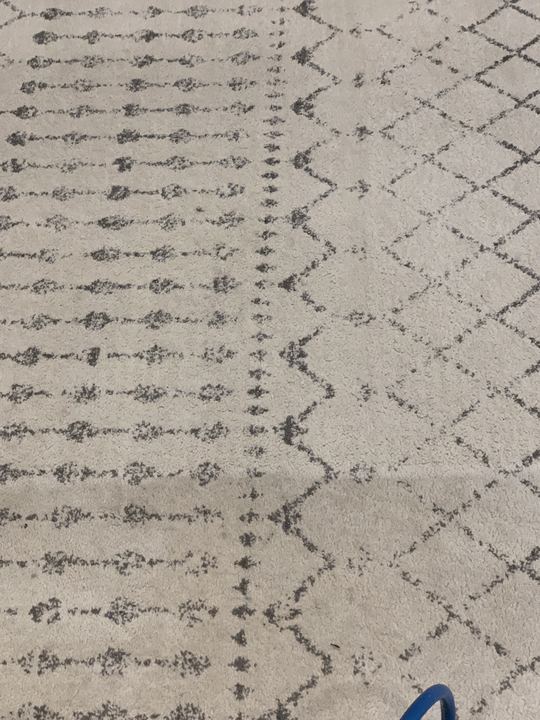 Cream diamond-pattern area rug half cleaned